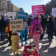 Marchers holding signs pass by the Trump International Hotel.